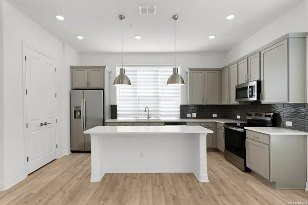 a large kitchen with stainless steel appliances granite countertop a stove a sink and a refrigerator