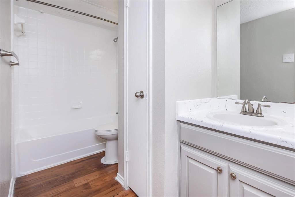 1826 Esters Road, Unit 1050 Irving, TX 75061 - Photo 28 of 39 Bathroom featuring a tub/shower combination with white subway tile, wood-finish flooring, a vanity with a drop-in sink, and brushed nickel fixtures