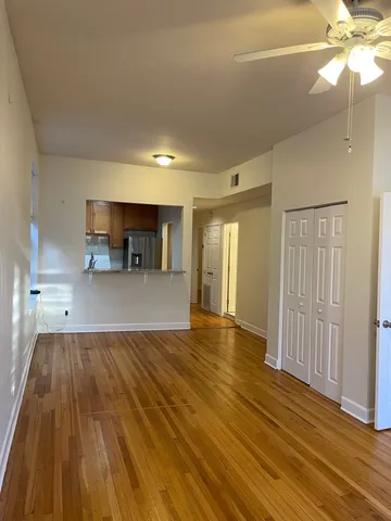 a view of a room with wooden floor and a kitchen space