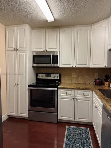 a kitchen with granite countertop a stove and a microwave