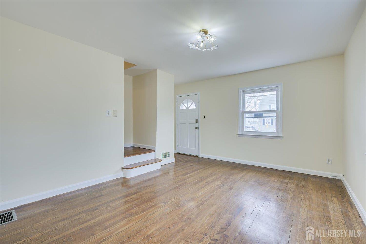 1 Coolidge Avenue Edison, NJ 08837 - Photo 10 of 27 an empty room with wooden floor chandelier and windows