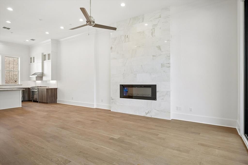 6019 Laurel Lane Addison, TX 75001 - Photo 10 of 21 Open-concept living area with wood-finish flooring, a contemporary fireplace with a large-format tile surround, recessed lighting, and a ceiling fan