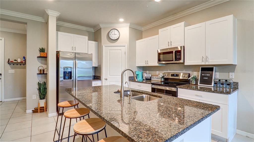 31632 Blue Passing Loop Wesley Chapel, FL 33545 - Photo 12 of 48 a kitchen with stainless steel appliances granite countertop a stove top oven a sink a counter space and cabinets
