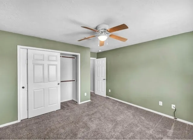 an empty room with closet and a ceiling fan