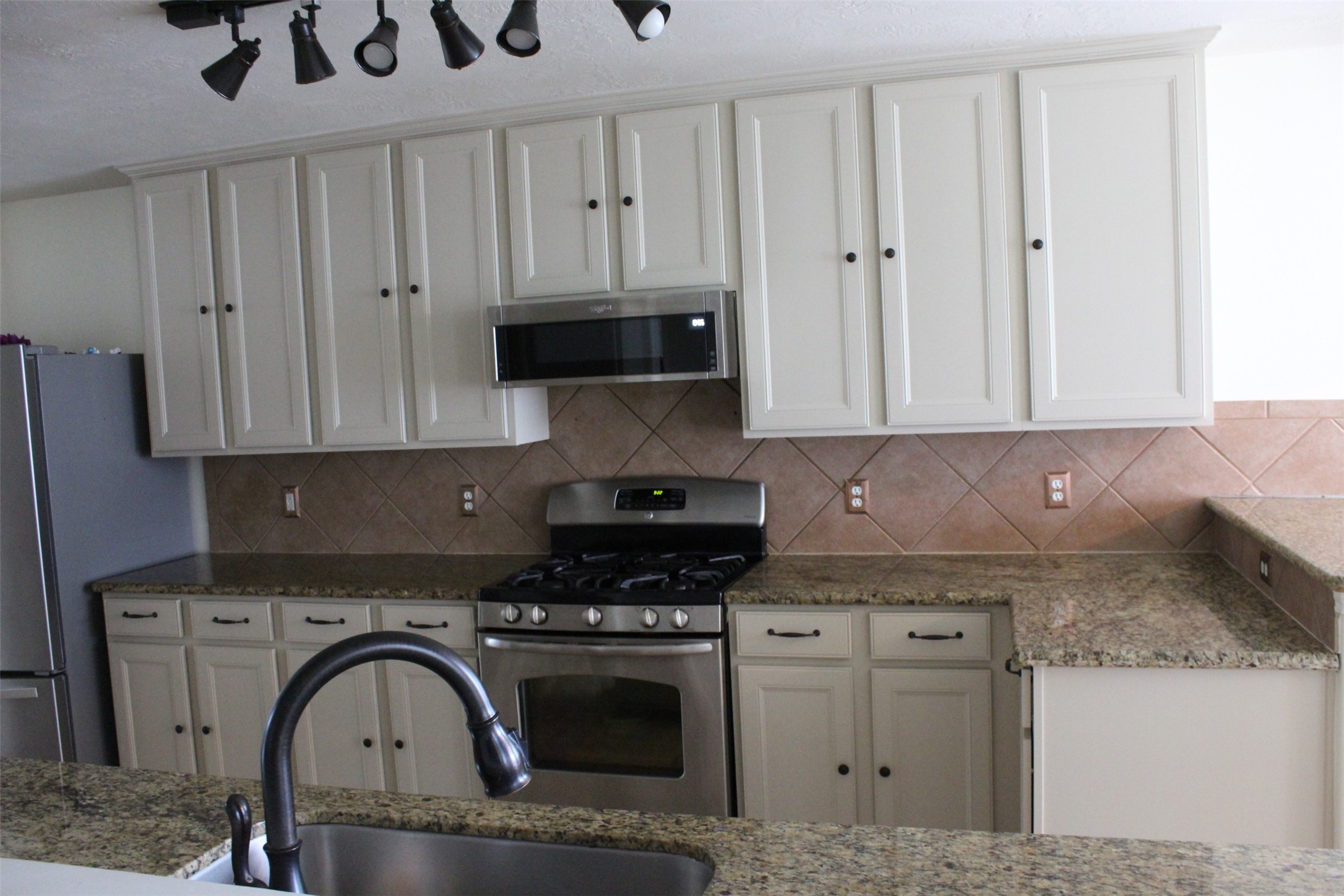 4507 Bridgestone Point Drive Spring, TX 77389 - Photo 4 of 21 a kitchen with granite countertop a stove a sink and a white wooden cabinets