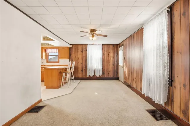 an empty room with chandelier fan and windows