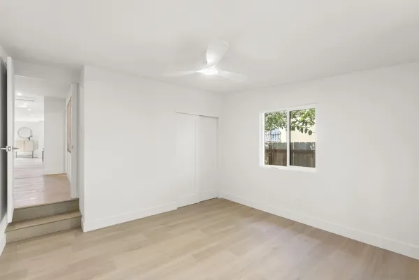 an empty room with wooden floor and windows