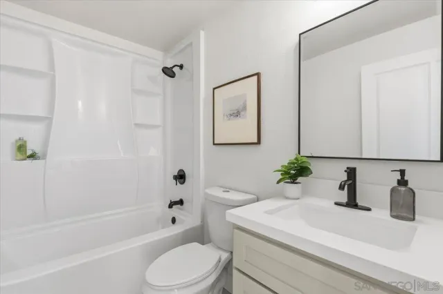 a bathroom with a sink a toilet a mirror a vanity and shower