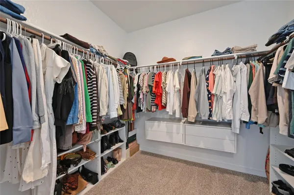 a view of walk in closet with clothes and shoes