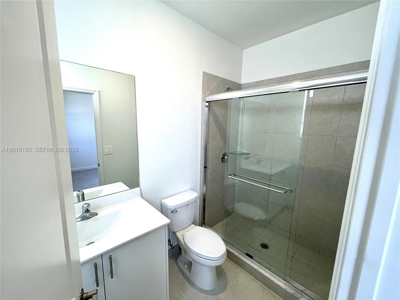 11737 Southwest 245 Terrace Homestead, FL 33032 - Photo 11 of 16 a bathroom with a shower sink vanity and a toilet