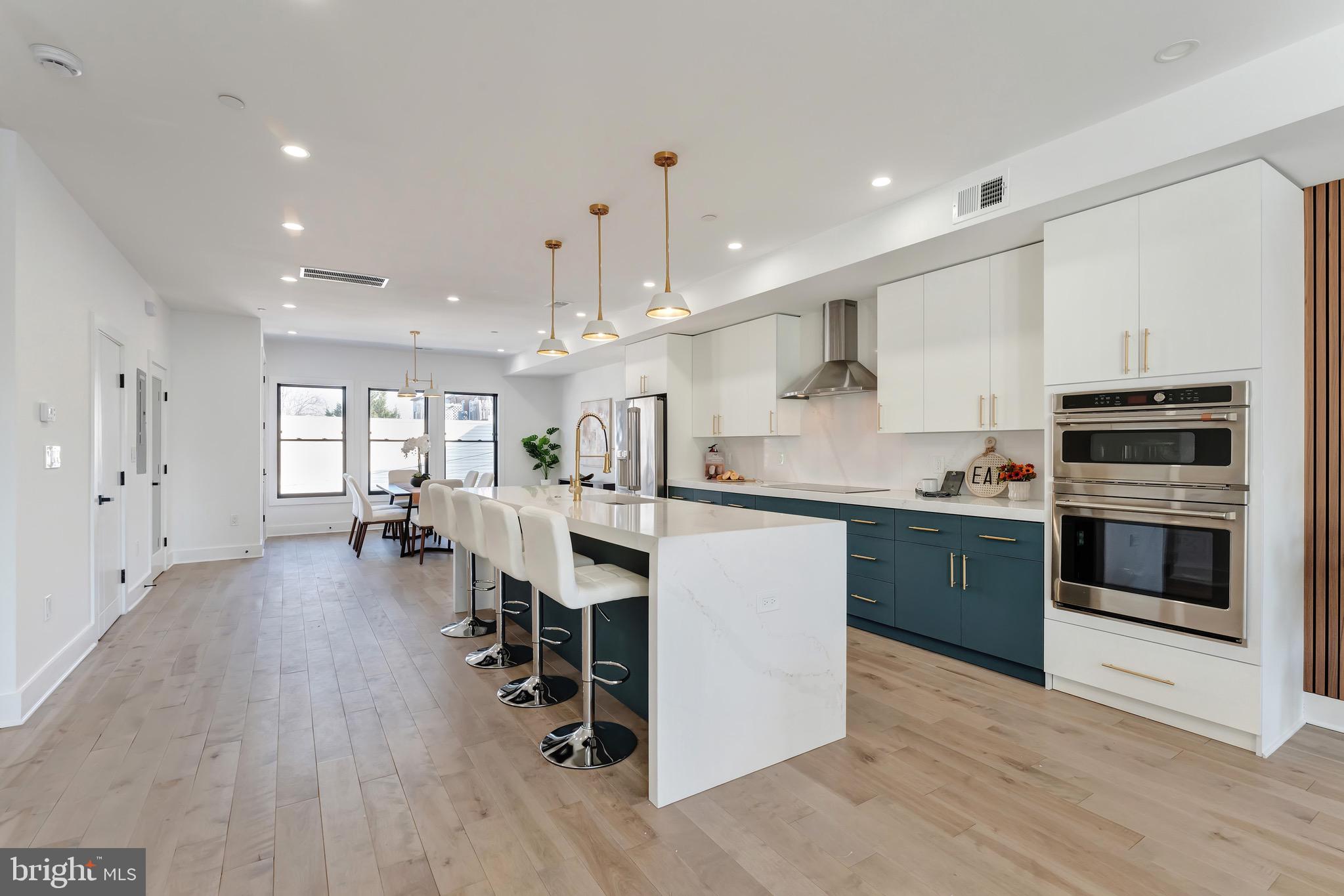 3009 13th Street Northwest, Unit 2 Washington, DC 20009 - Photo 13 of 44 a kitchen with stainless steel appliances kitchen island wooden floors stove and white cabinets