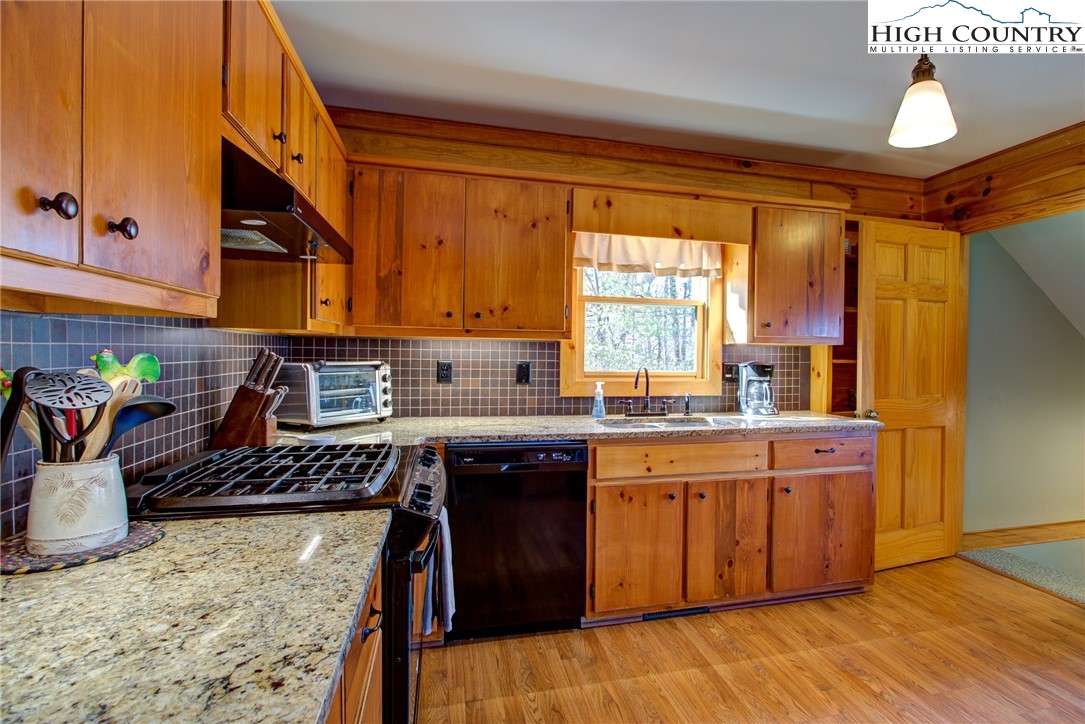 1643 Buck Mountain Road Purlear, NC 28665 - Photo 4 of 33 a kitchen with stainless steel appliances granite countertop a stove a sink dishwasher and cabinets with wooden floor
