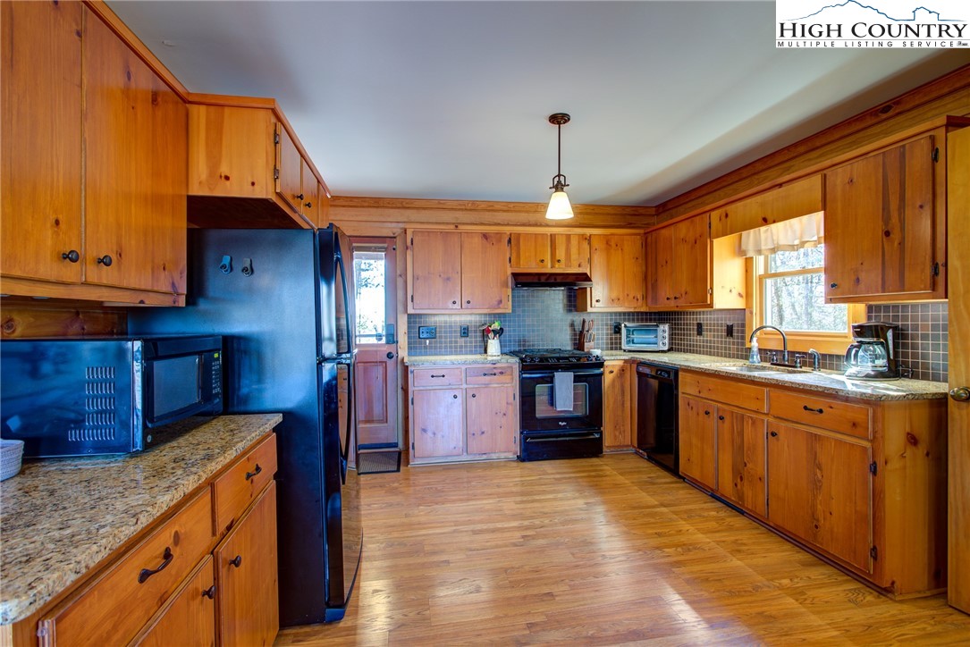1643 Buck Mountain Road Purlear, NC 28665 - Photo 5 of 33 a kitchen with stainless steel appliances kitchen island granite countertop a refrigerator a sink dishwasher a stove with wooden cabinets and floor