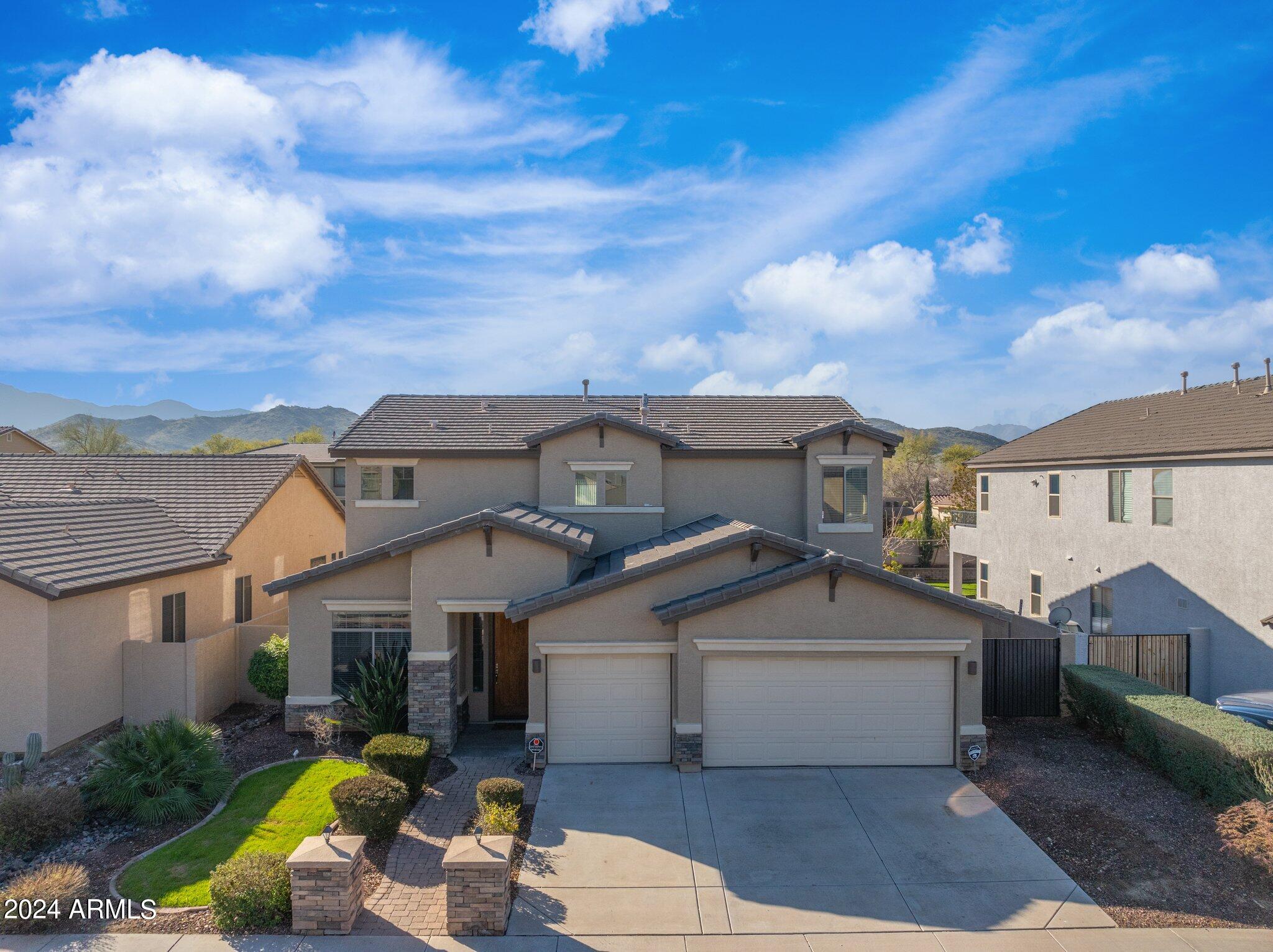 a view of a white house with a fountain plants and large tree