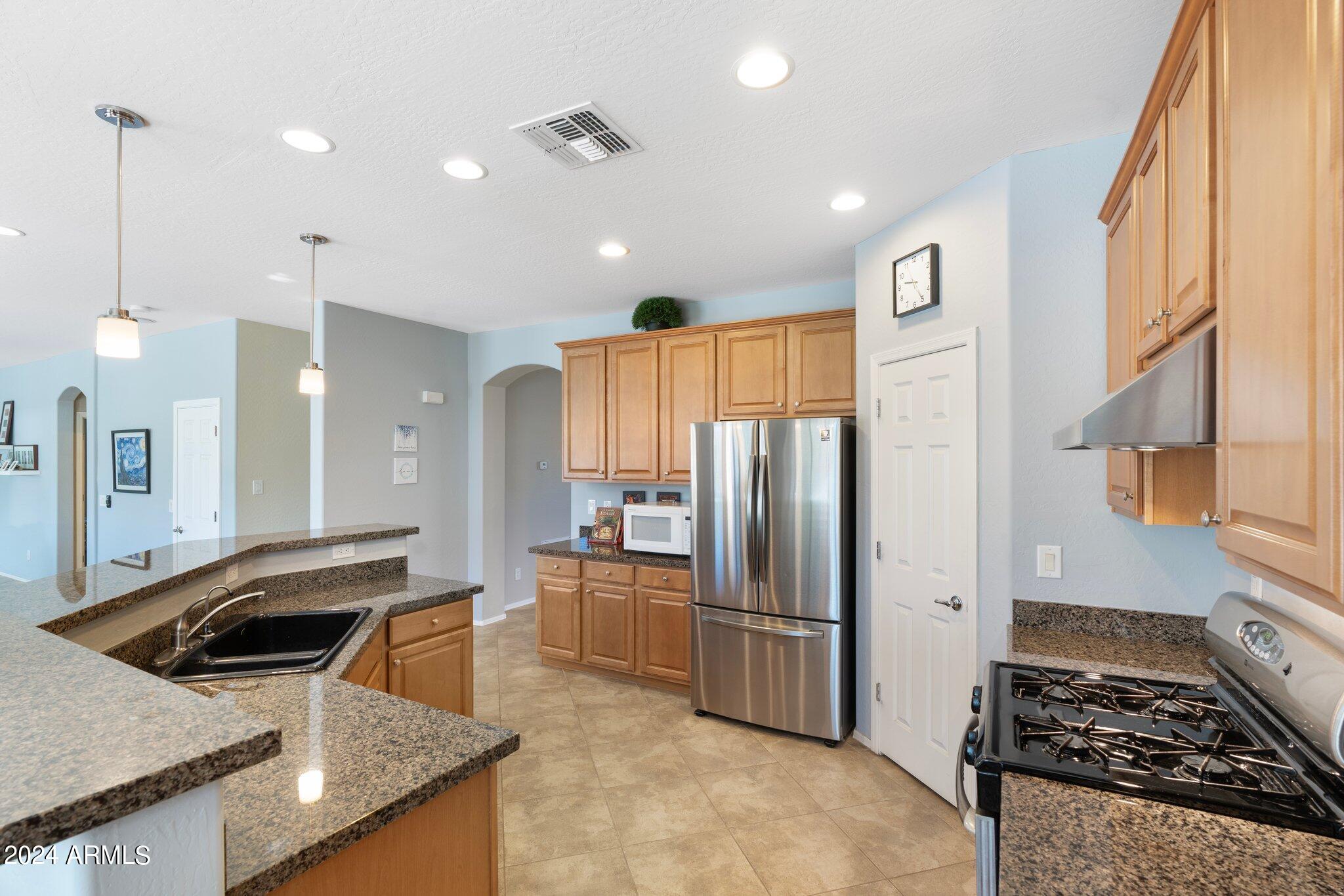 4427 West Summerside Road Laveen, AZ 85339 - Photo 7 of 72 a kitchen with stainless steel appliances granite countertop a sink stove and refrigerator