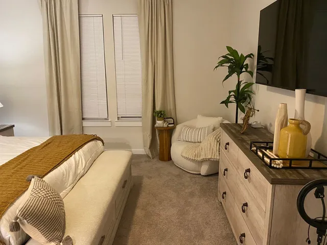 a bedroom with a bed a couch and potted plant