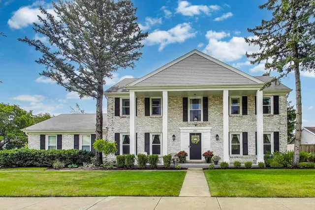 a front view of a house with a yard and trees