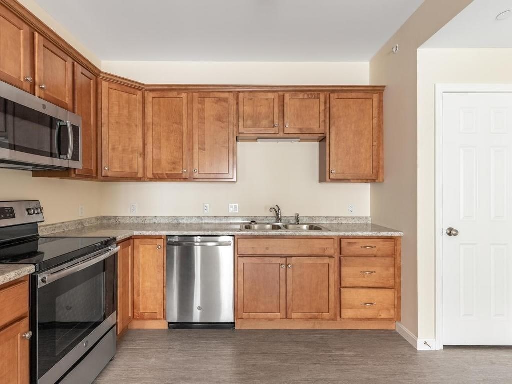 73 North Common Street, Unit 12 Lynn, MA 01902 - Photo 3 of 30 a kitchen with stainless steel appliances granite countertop a stove a sink and a microwave
