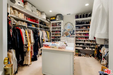 a view of walk in closet with clothes and shoes