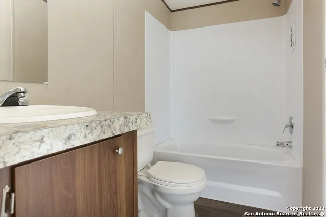 a bathroom with a granite countertop sink toilet mirror vanity and bathtub