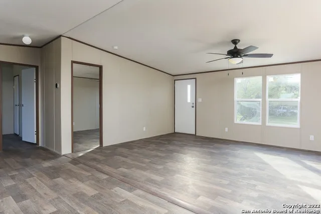 an empty room with windows and chandelier fan