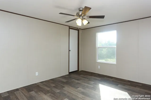 an empty room with a chandelier fan and windows