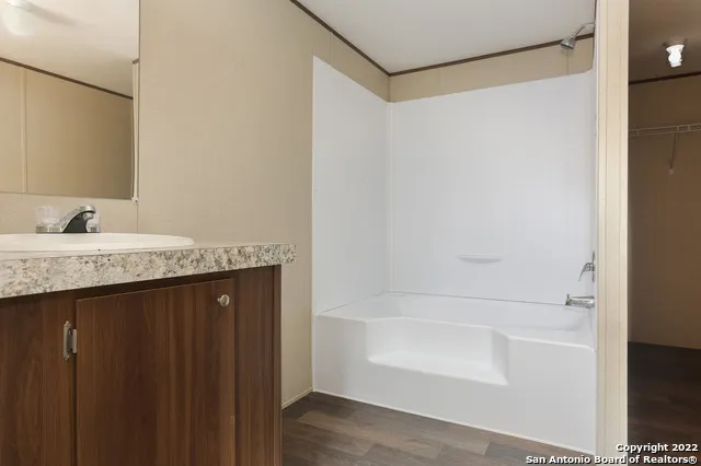 a bathroom with a granite countertop sink and a shower