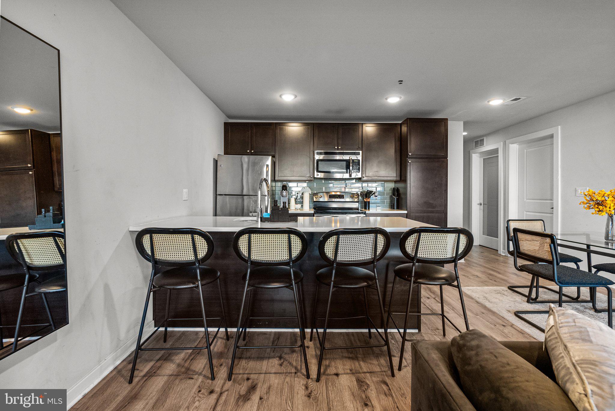 1608 Ridge Avenue, Unit 302 Philadelphia, PA 19130 - Photo 12 of 24 a kitchen with stainless steel appliances kitchen island granite countertop a dining table chairs and a refrigerator