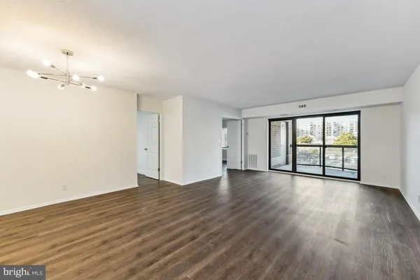 a view of an empty room with a window and wooden floor