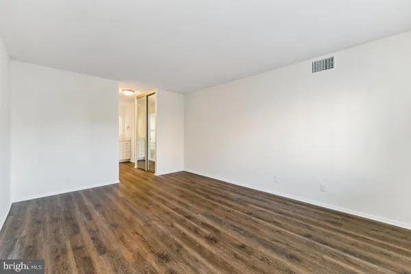 a view of an empty room with wooden floor and window