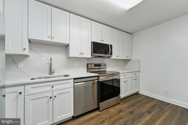 a kitchen with granite countertop white cabinets and stainless steel appliances