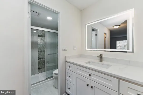 a bathroom with a shower sink vanity mirror and toilet