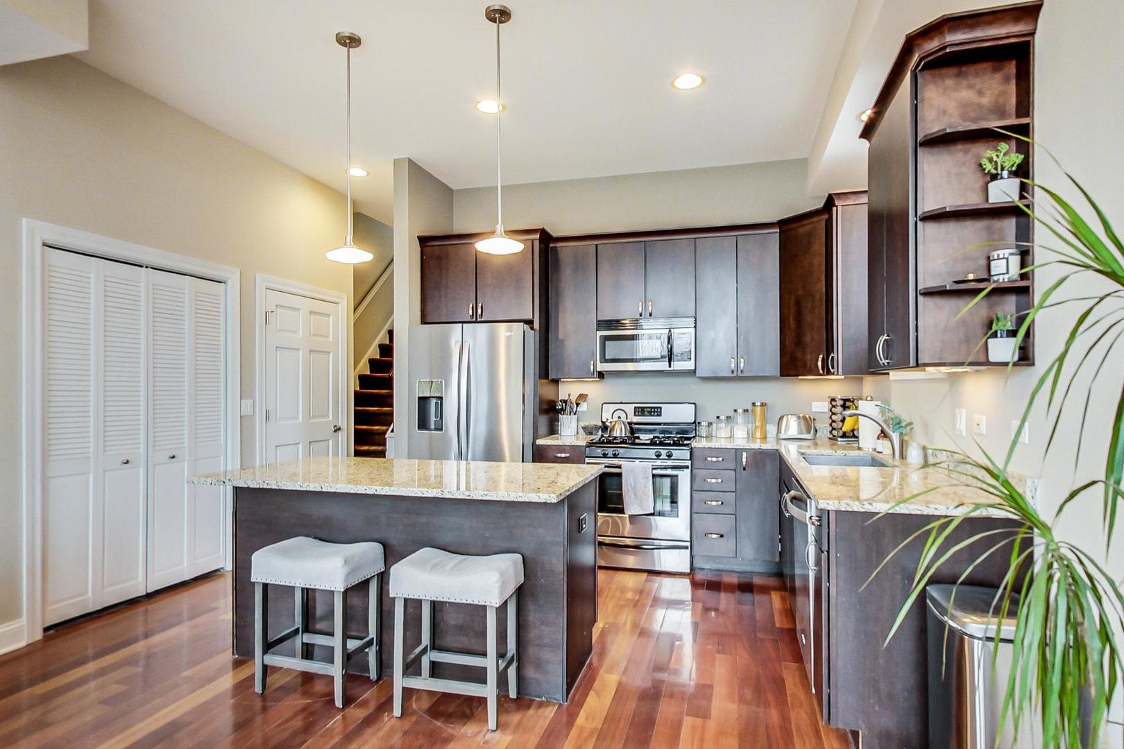 3605 South Leavitt Street, Unit 3 Chicago, IL 60609 - Photo 7 of 22 a kitchen with stainless steel appliances granite countertop a refrigerator a sink dishwasher a stove and a dining table with wooden floor