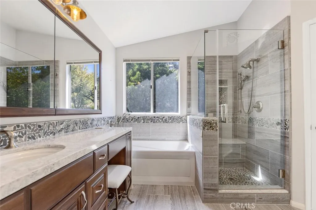 27619 Ron Ridge Drive Saugus, CA 91350 - Photo 20 of 37 a bathroom with a granite countertop sink a mirror a bathtub and next to a window