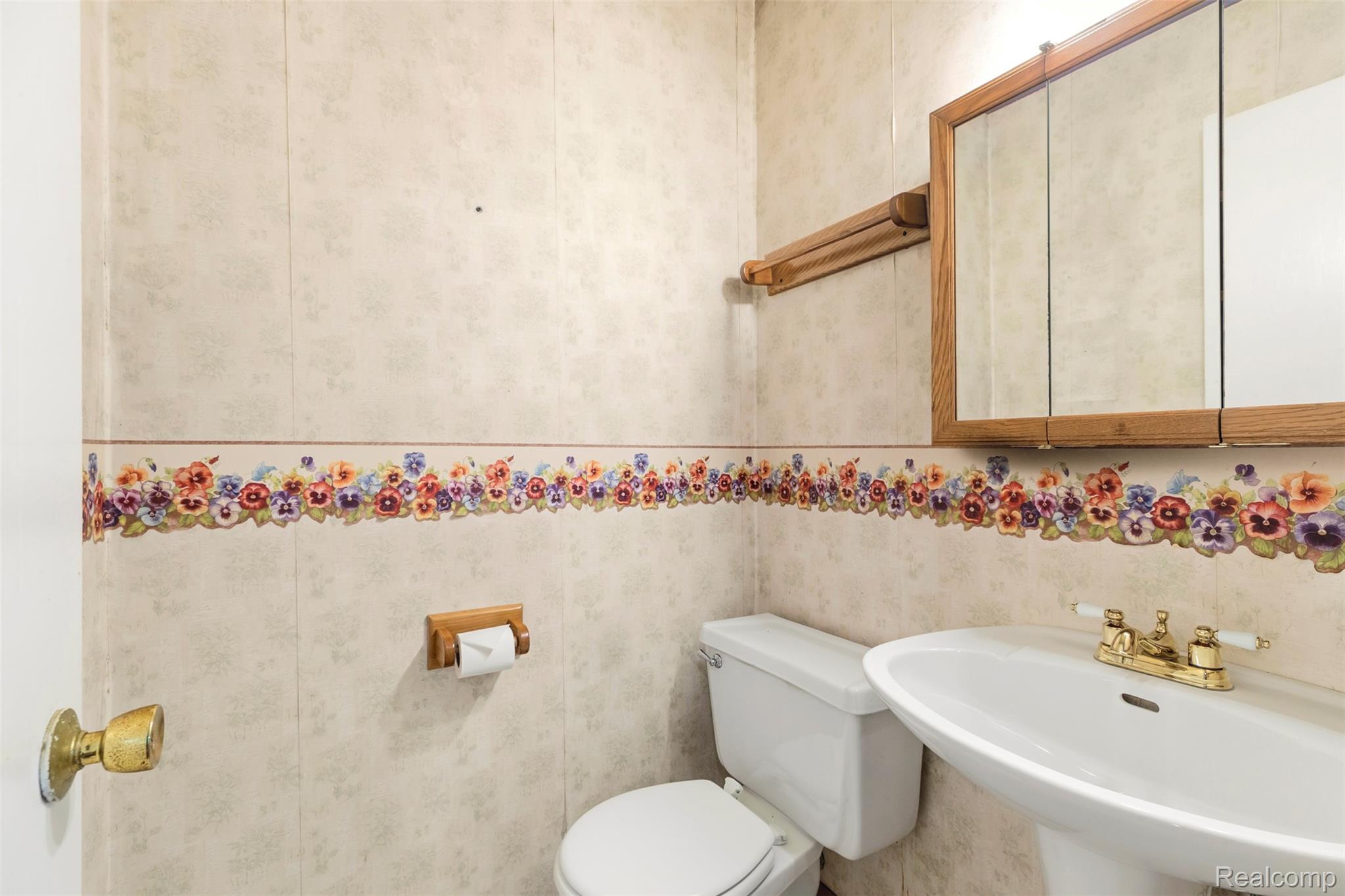 309 Windy Bluff Street Flushing, MI 48433 - Photo 11 of 32 Bathroom featuring a pedestal sink with brass-finish faucet, toilet, and a wood-framed medicine cabinet