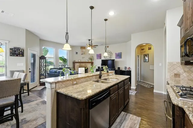 a kitchen with stainless steel appliances granite countertop a sink a stove and a wooden cabinets