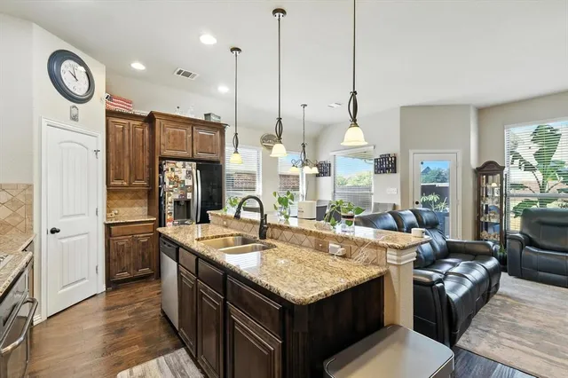 a kitchen with stainless steel appliances granite countertop a sink a stove and a refrigerator