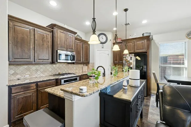 a kitchen with granite countertop kitchen island stainless steel appliances a stove a sink a refrigerator a dining table chairs and couches