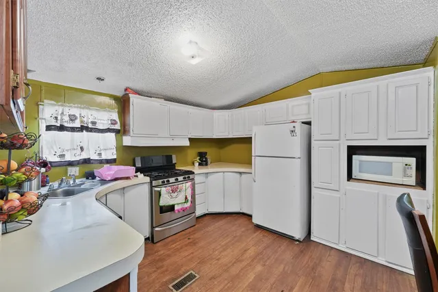 a view of a kitchen with fridge and wooden floor
