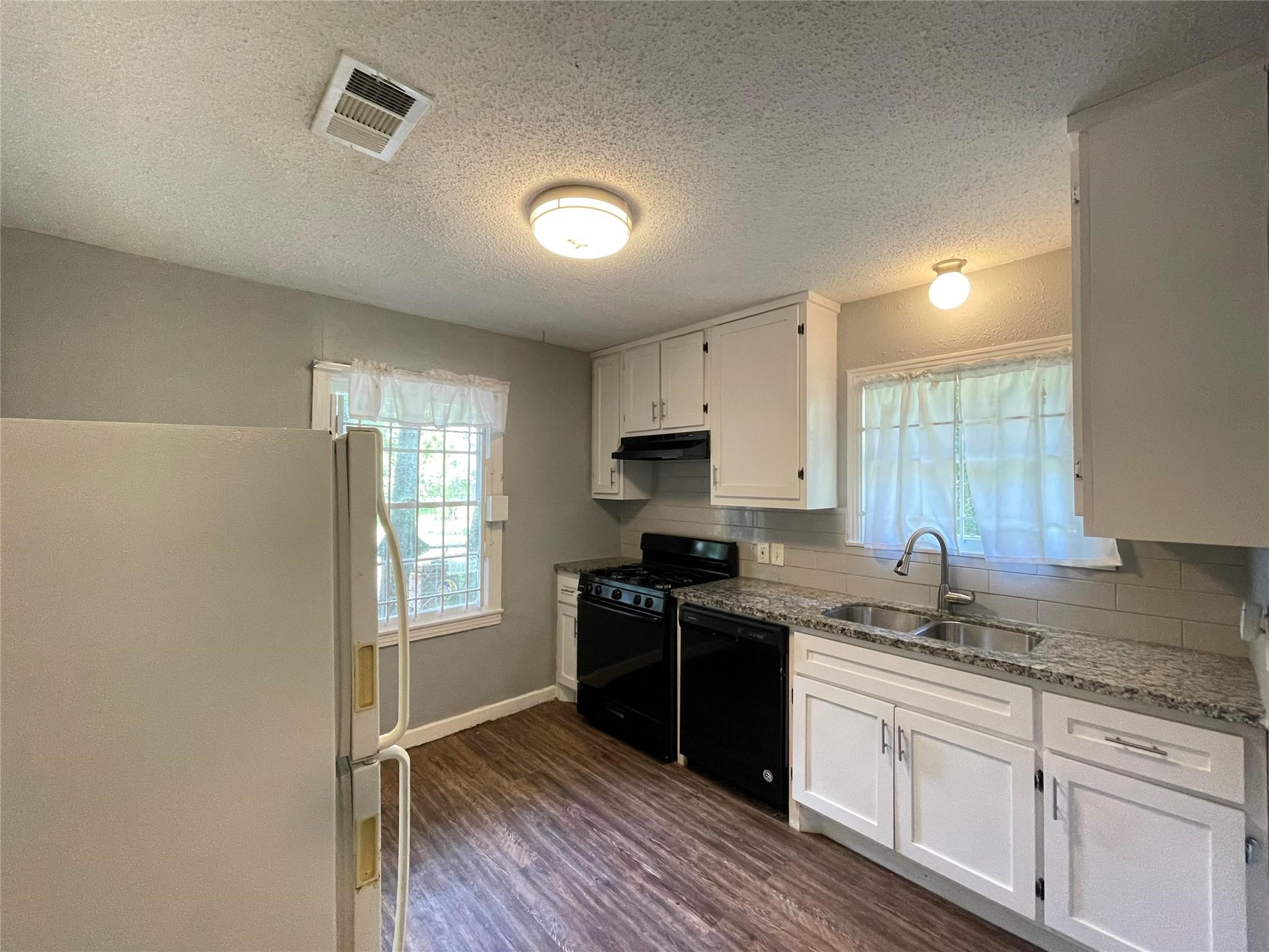 5213 Anzio Road Houston, TX 77033 - Photo 7 of 20 a kitchen with granite countertop a sink cabinets wooden floor and stainless steel appliances