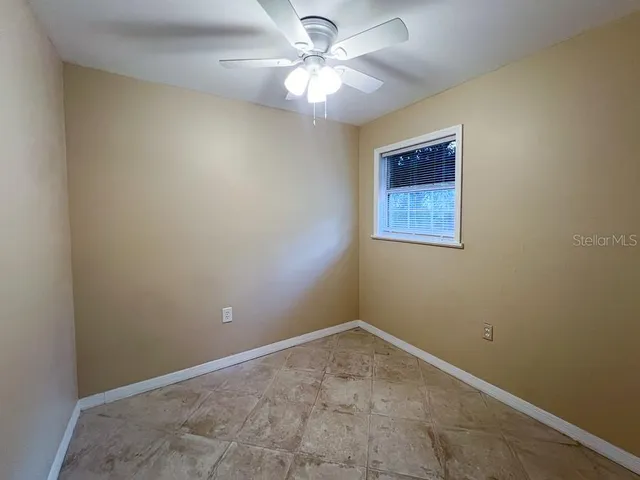 an empty room with a window and a fan