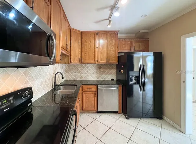 a kitchen with stainless steel appliances granite countertop a refrigerator a stove and a sink
