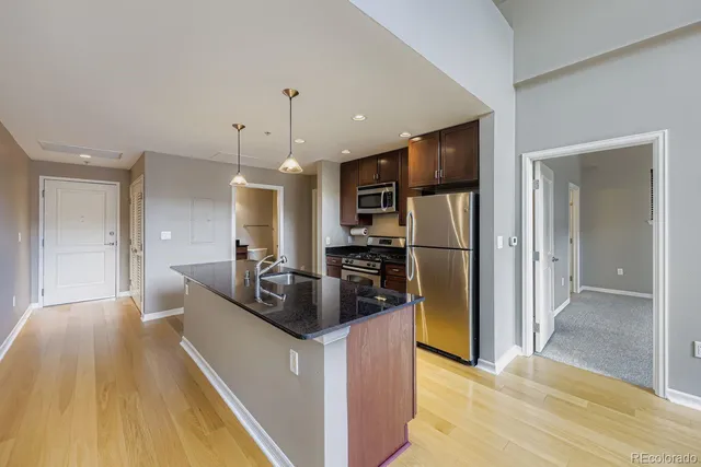 a kitchen view with stainless steel appliances kitchen island granite countertop a refrigerator and a sink