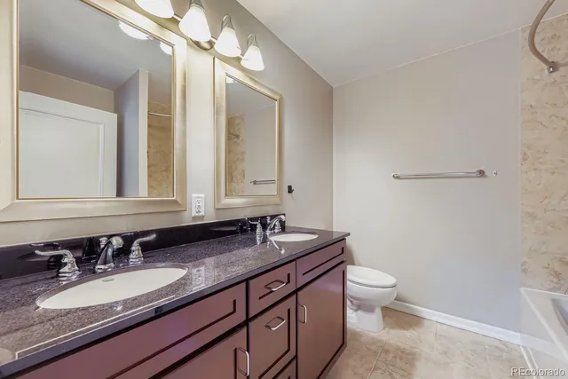 a bathroom with a granite countertop sink a toilet and a mirror