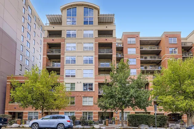 a front view of a building with lot of plants and trees