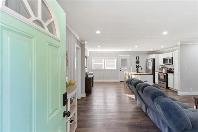 a large kitchen with stainless steel appliances kitchen island granite countertop a refrigerator a stove a microwave oven a dining table and chairs with wooden floor