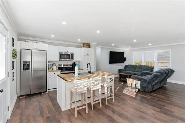 a large kitchen with stainless steel appliances kitchen island granite countertop a refrigerator a stove a microwave oven a dining table and chairs with wooden floor