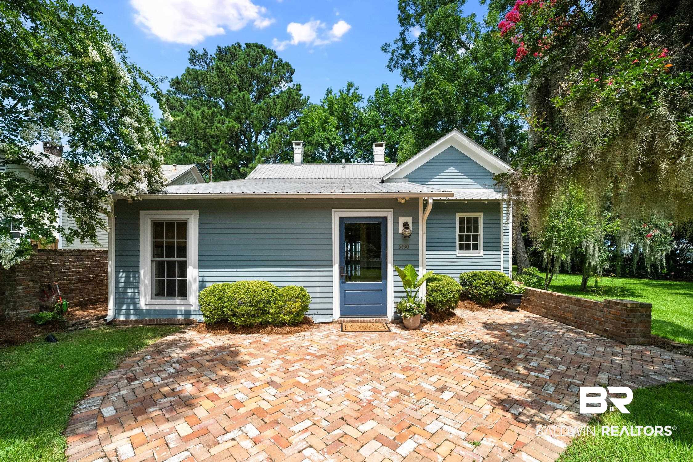 5490 Battles Road Fairhope, AL 36532 - Photo 2 of 47 Coastal blue siding exterior with a metal roof, featuring a herringbone brick patio