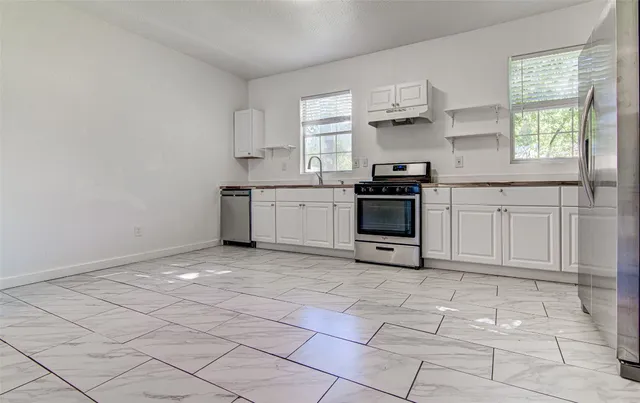 a kitchen with stainless steel appliances granite countertop a stove a sink and white cabinets