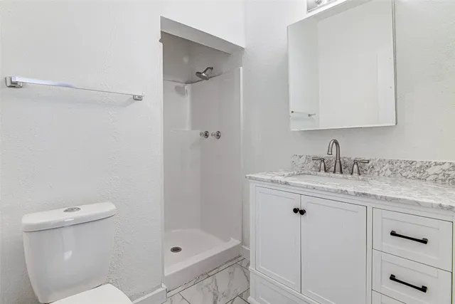 a bathroom with a granite countertop sink a toilet and shower